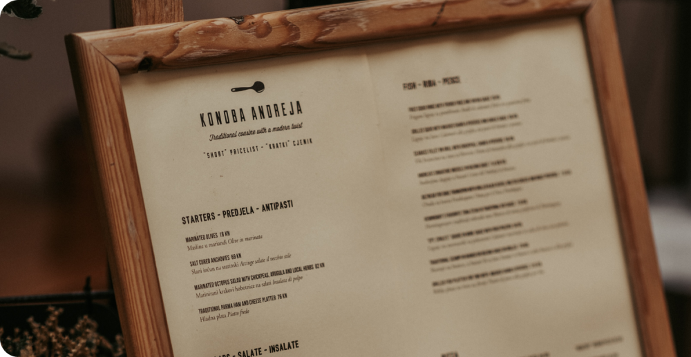 Un menu alléchant présenté sur un support en bois, mettant en valeur les différentes pizzas saisonnières.